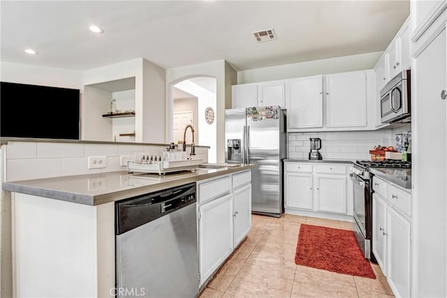 kitchen featuring a center island with sink, visible vents, decorative backsplash, white cabinets, and appliances with stainless steel finishes