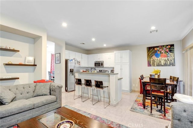 living room with light tile patterned flooring, visible vents, and recessed lighting