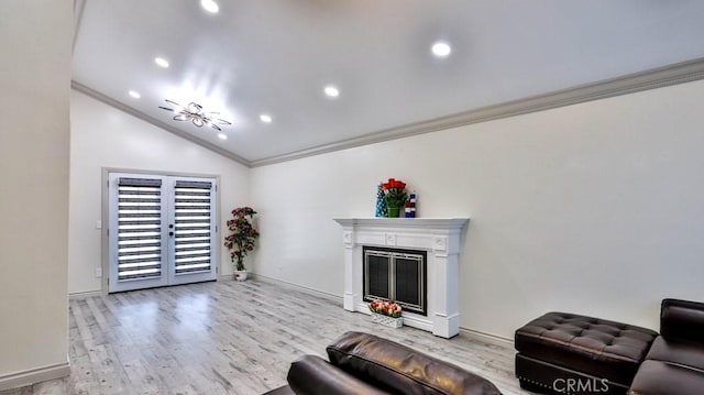 living room with a glass covered fireplace, crown molding, light wood-style floors, and vaulted ceiling