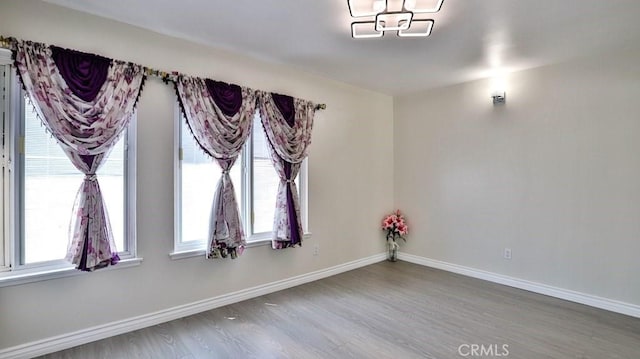 empty room featuring baseboards, plenty of natural light, and wood finished floors