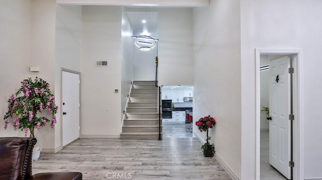 stairs with visible vents, a high ceiling, baseboards, and wood finished floors