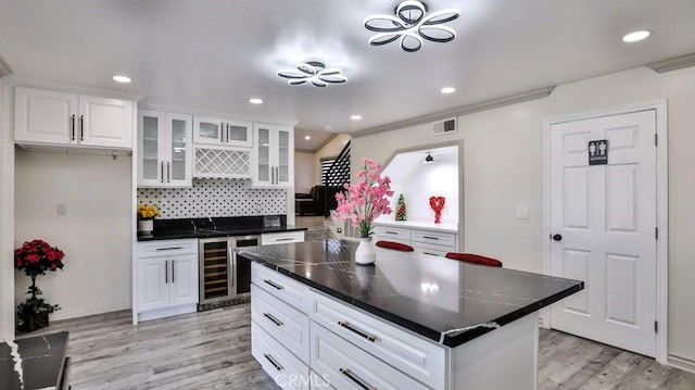 kitchen with visible vents, light wood-type flooring, wine cooler, dark countertops, and tasteful backsplash