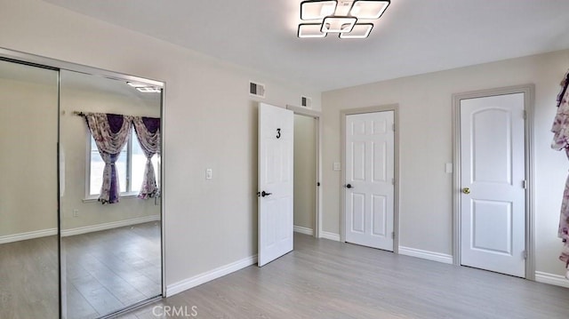 unfurnished bedroom featuring baseboards, visible vents, and light wood-type flooring