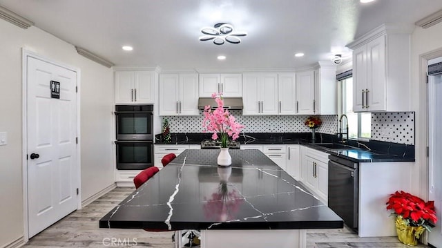 kitchen with black appliances, a sink, under cabinet range hood, dark countertops, and white cabinets