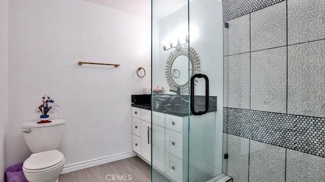 full bath featuring a shower stall, baseboards, toilet, wood finished floors, and vanity