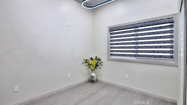 spare room featuring baseboards and wood finished floors