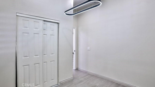 unfurnished bedroom featuring light wood-style floors, baseboards, and a closet