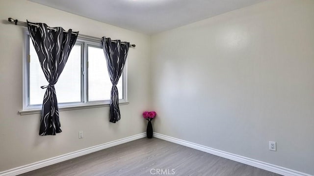 spare room featuring wood finished floors and baseboards