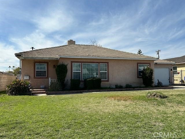 view of side of home with a tile roof, stucco siding, a chimney, a yard, and a garage