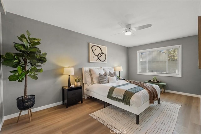 bedroom featuring ceiling fan, baseboards, and wood finished floors