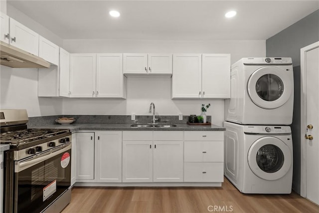 laundry room featuring stacked washer and clothes dryer, a sink, recessed lighting, light wood finished floors, and laundry area