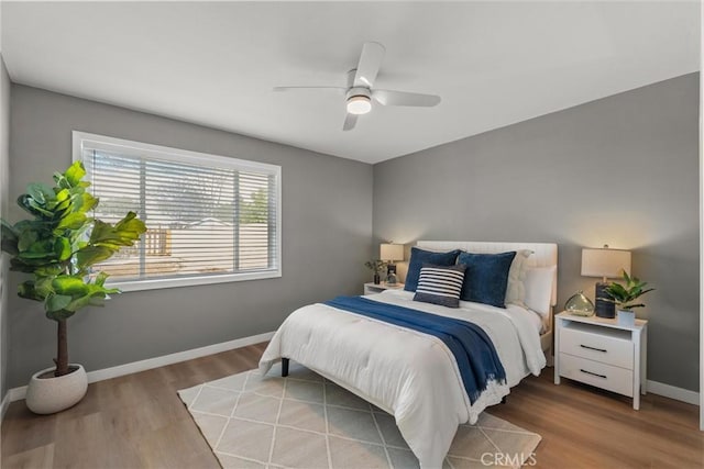 bedroom featuring ceiling fan, baseboards, and wood finished floors