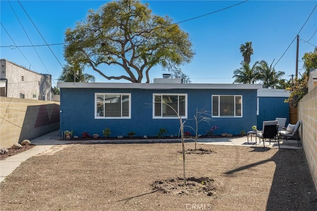 rear view of house with a patio, fence, and stucco siding