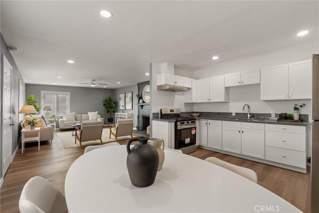 kitchen featuring dark countertops, recessed lighting, wood finished floors, gas stove, and a sink