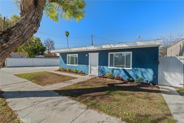 view of front of house featuring stucco siding, concrete driveway, and fence