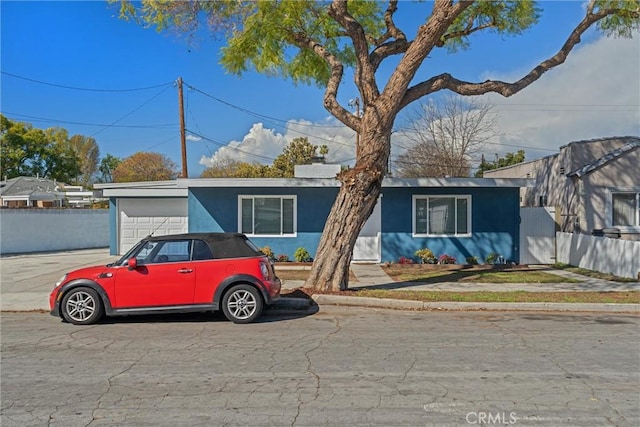 view of front of home featuring an attached garage, fence, and stucco siding