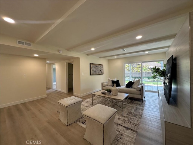 living room featuring visible vents, beamed ceiling, baseboards, and light wood-style floors