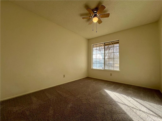 spare room featuring a ceiling fan, baseboards, vaulted ceiling, a textured ceiling, and dark carpet