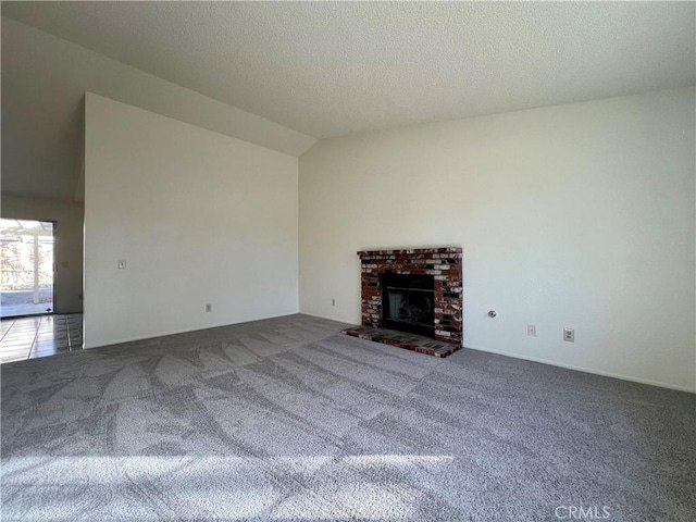 unfurnished living room featuring lofted ceiling, carpet flooring, a fireplace, and a textured ceiling