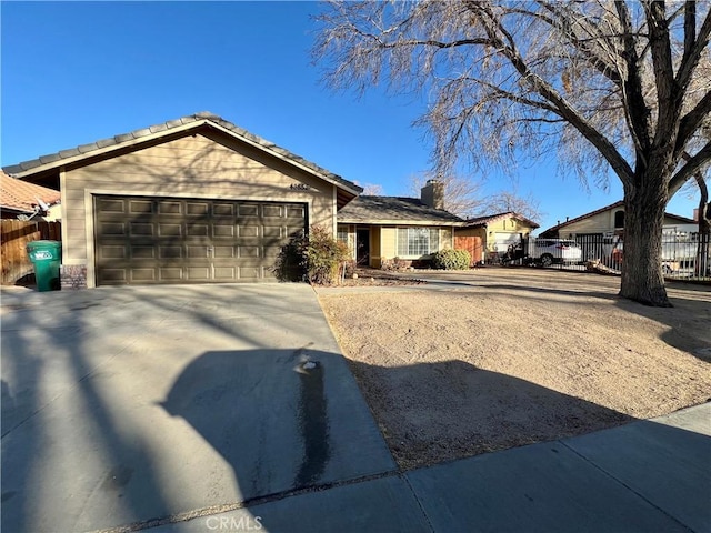 single story home featuring a garage, concrete driveway, and fence