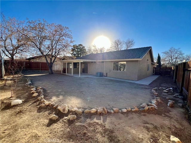 view of front facade featuring a patio, a fenced backyard, central AC, and stucco siding