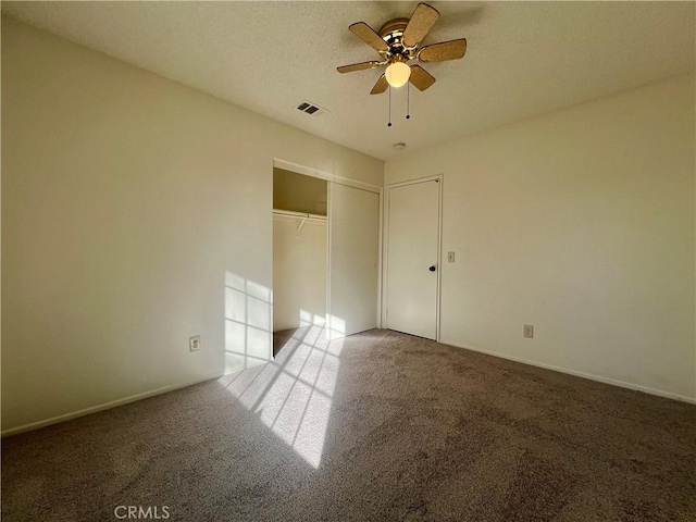 unfurnished bedroom with visible vents, a textured ceiling, a closet, carpet, and baseboards