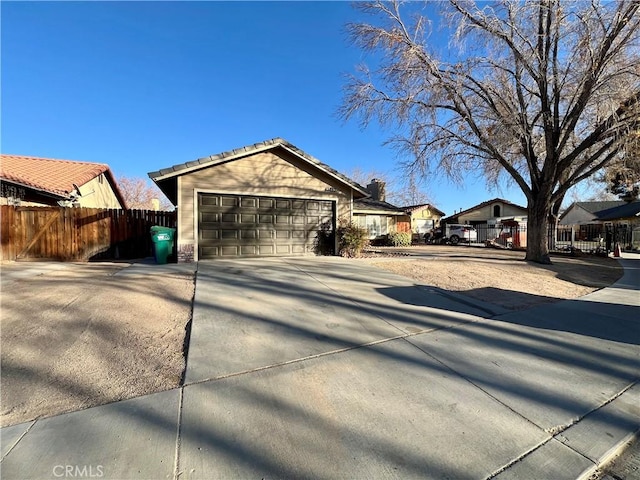 exterior space with concrete driveway, an attached garage, fence, and a residential view