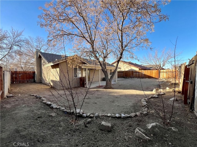 rear view of property featuring a fenced backyard, stucco siding, a tiled roof, and a patio