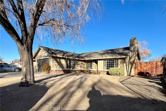 single story home with driveway, a chimney, an attached garage, and fence