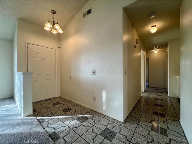 foyer with visible vents, baseboards, a textured ceiling, and an inviting chandelier