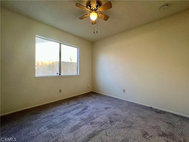 carpeted empty room featuring baseboards and a ceiling fan