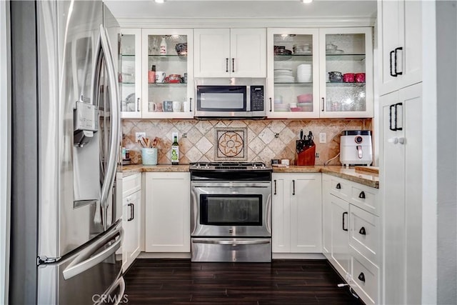 kitchen featuring light stone counters, dark wood-style flooring, white cabinets, appliances with stainless steel finishes, and tasteful backsplash