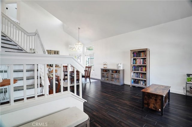 interior space featuring an inviting chandelier, wood finished floors, baseboards, and high vaulted ceiling