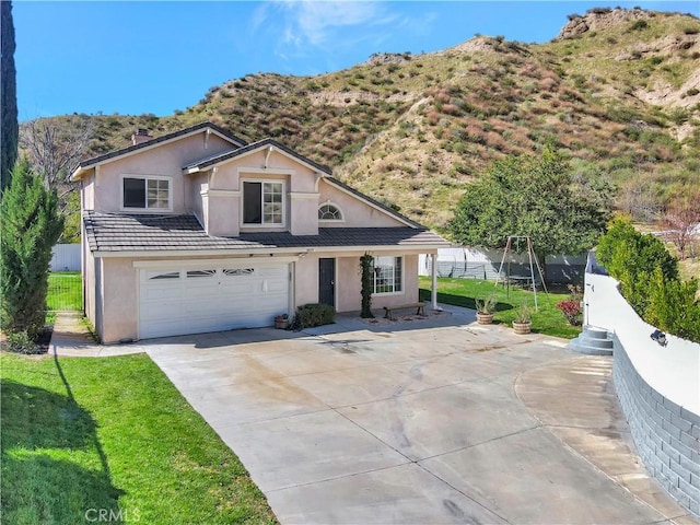 traditional-style house with a trampoline, fence, stucco siding, a garage, and driveway