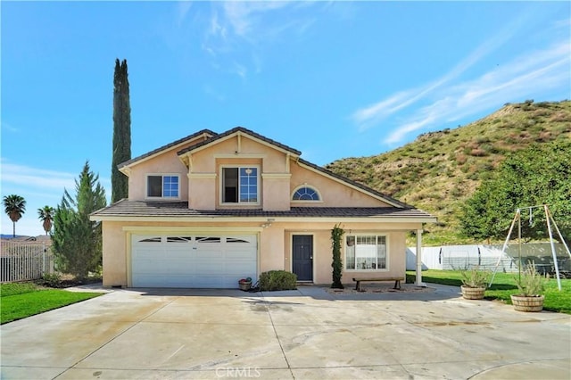 traditional home with fence, a garage, driveway, and stucco siding