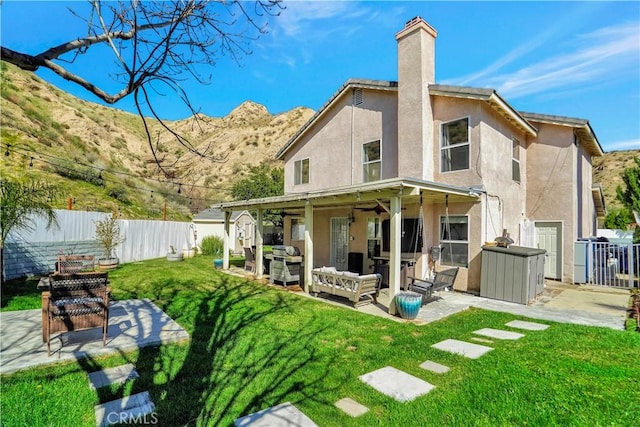 back of house featuring a patio, fence private yard, a lawn, and stucco siding