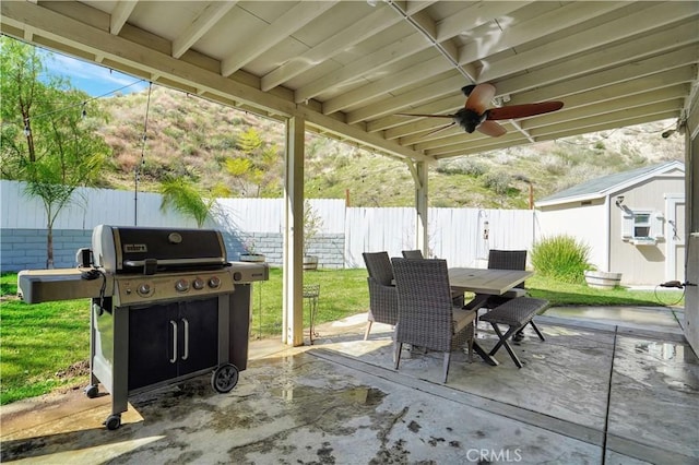 view of patio with an outbuilding, outdoor dining space, a grill, and a fenced backyard