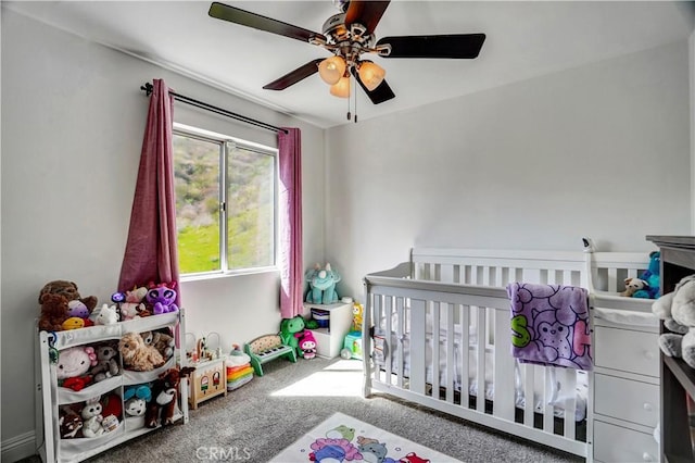 bedroom with a ceiling fan, a nursery area, and carpet flooring