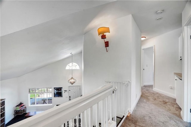 hall with baseboards, an upstairs landing, light colored carpet, and lofted ceiling