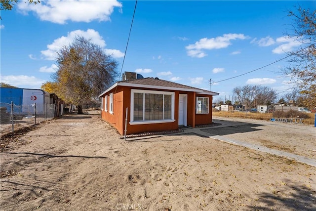 back of property featuring stucco siding and fence