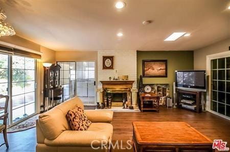 living room with wood finished floors, recessed lighting, and a fireplace with raised hearth