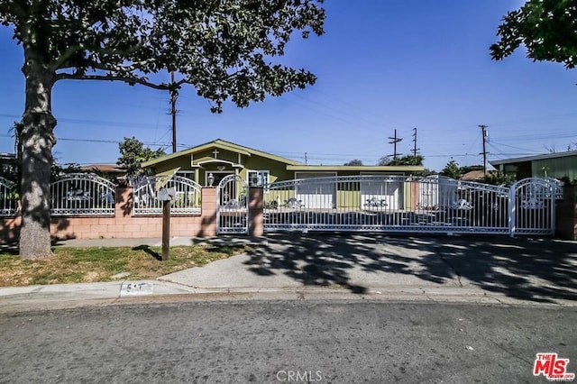 view of front of property featuring concrete block siding, a gate, and a fenced front yard