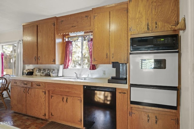 kitchen with a warming drawer, a sink, backsplash, black dishwasher, and tile counters