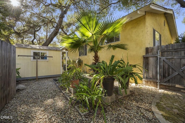 view of side of property with a gate, an outbuilding, a storage shed, and fence