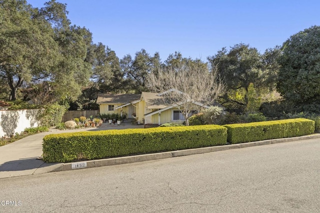 view of front facade with concrete driveway and fence