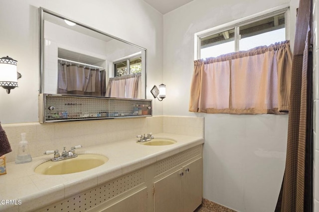 full bathroom featuring double vanity, a healthy amount of sunlight, and a sink