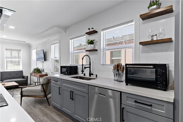 kitchen with stainless steel dishwasher, open shelves, a sink, and gray cabinetry