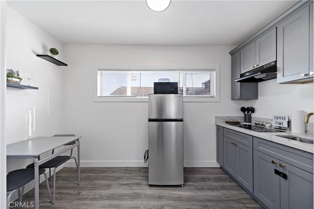 kitchen featuring under cabinet range hood, gray cabinetry, black appliances, and a sink