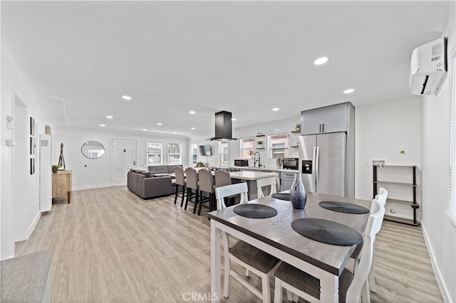 dining room featuring recessed lighting, baseboards, light wood-type flooring, and a wall unit AC