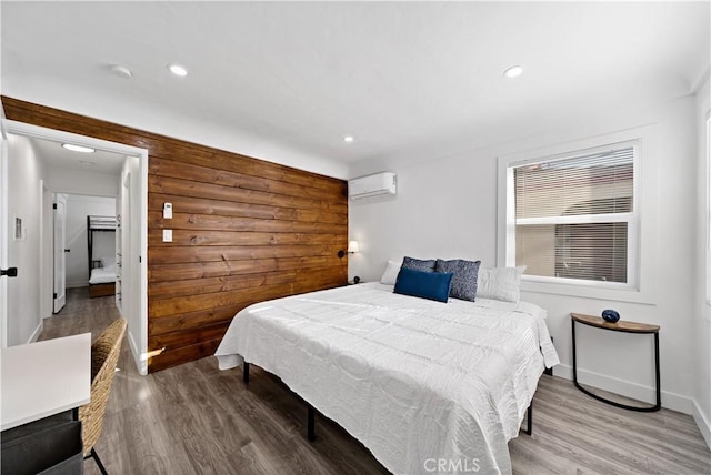 bedroom featuring recessed lighting, baseboards, an AC wall unit, and wood finished floors